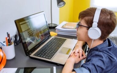 Student attending to an online class wearing a white pair of headphones