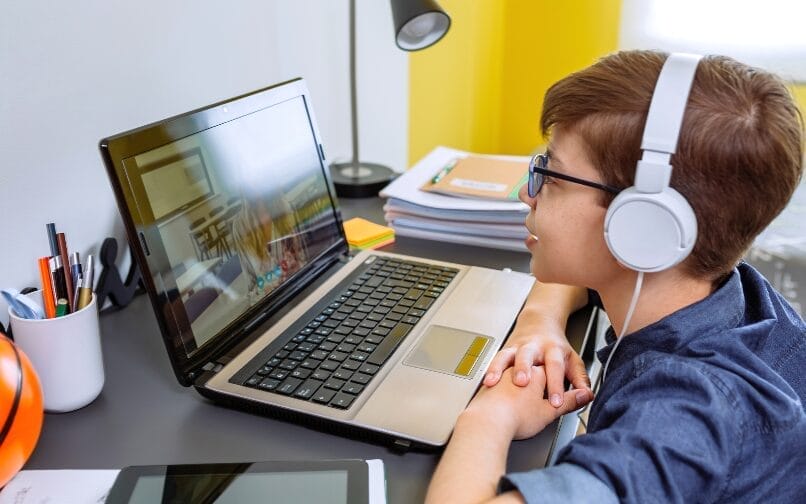 Student attending to an online class wearing a white pair of headphones