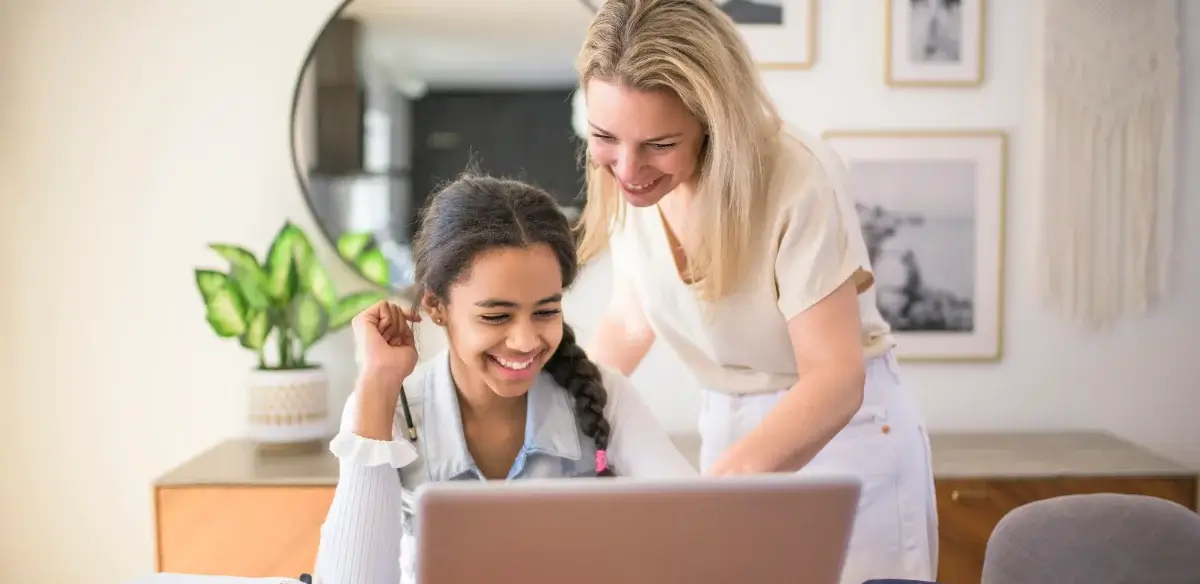 mom and girl looking the computer and smiling